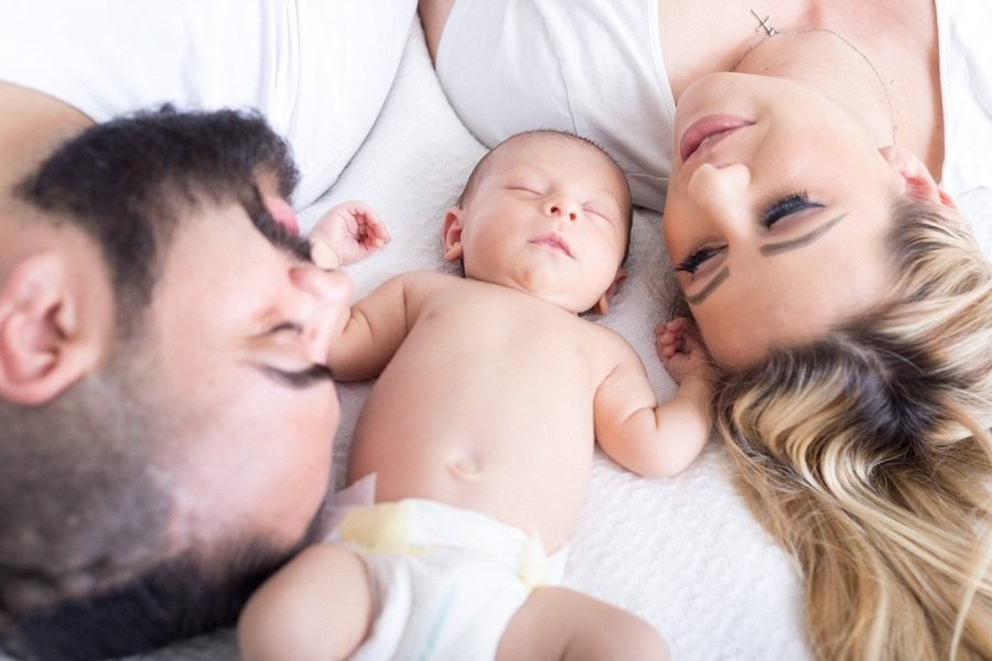 couple lying in bed with their newborn baby