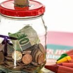 glass savings jar containing notes and coins